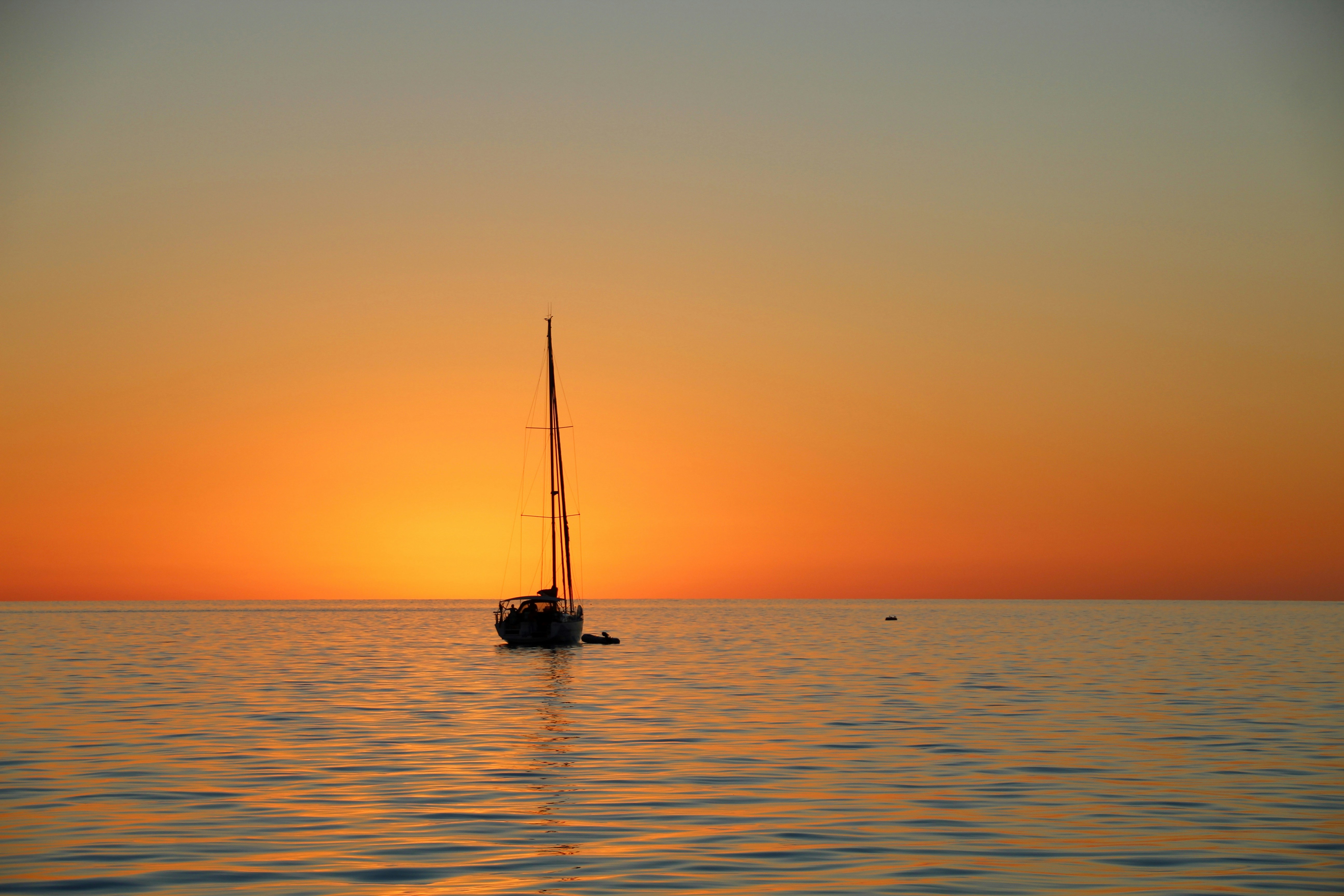 monohull sailboat sailing into the sunset